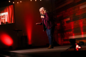 Tracy DeGraaf speaking on stage at a breast cancer awareness event